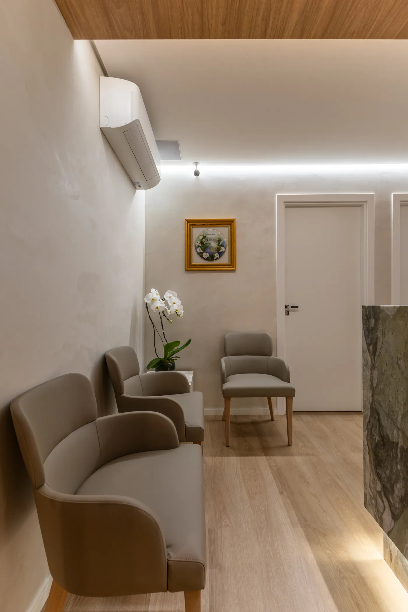 Sala de espera com poltronas, orquídea e iluminação indireta